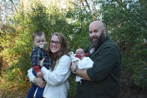 Joel Rightler with his wife and two young children, outdoors in autumn